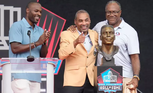 Former NFL player Roger Craig, center, unveils his bust with son, Roderick Craig, left, and Jamie Williams during the Pro Football Hall of Fame induction ceremony at the Pro Football Hall of Fame, in Canton, Ohio, Saturday, Aug. 8, 2026. (AP Photo/Sue Ogrocki)