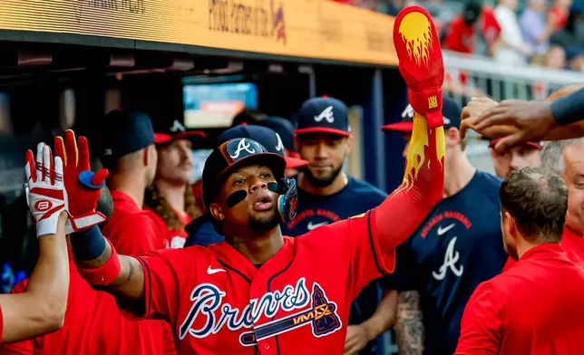 Atlanta Braves' Ronald Acuña Jr., center, is greeted in the dugout after scoring against the Colorado Rockies during the second inning of a baseball game, Friday, Aug. 28, 2026, in Atlanta. (AP Photo/Erik S. Lesser)