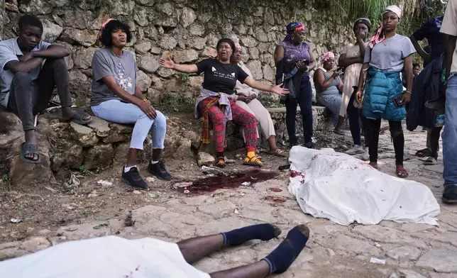 People gather next to the bodies of people they said were their relatives and were killed in a gang attack in the Kenscoff neighborhood of Port-au-Prince, Haiti, Monday, Aug. 24, 2026. (AP Photo/Odelyn Joseph)