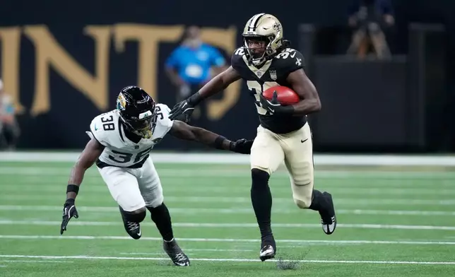 New Orleans Saints running back Ty Chandler, right, runs with the ball past Jacksonville Jaguars cornerback Corey Ballentine during the first half of an NFL preseason football game Saturday, Aug. 15, 2026, in New Orleans. (AP Photo/Gerald Herbert)
