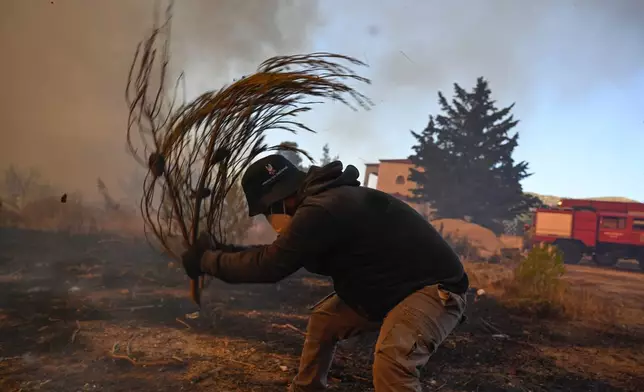 A volunteer tries to extinguish small flames during a wildfire near Porto Germeno, northwest of Athens, Greece, Sunday, Aug. 2, 2026. (AP Photo/Michael Varaklas)