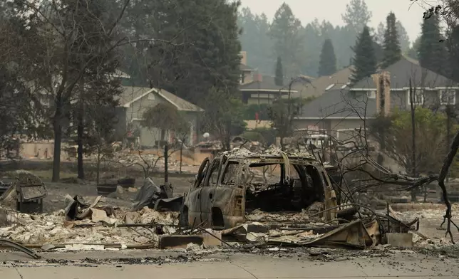 A vehicle and structure are burned on N. Skyline Dr. due to a wildfire, Sunday, Aug. 2, 2026, in Spokane, Wash. (AP Photo/Young Kwak)