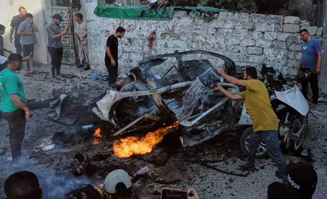 EDS NOTE: GRAPHIC CONTENT - Palestinians try to extinguish a burning car after an Israeli military strike in Gaza City, Sunday, Aug. 2, 2026. (AP Photo/Jehad Alshrafi)