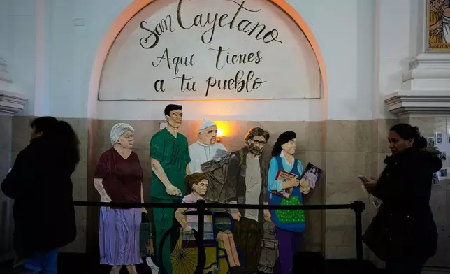 An art installation with a message that reads in Spanish: "Here are your people" and that includes a depiction of Pope Leo XIV is on display inside the Church of San Cayetano during the annual pilgrimage honoring Saint Cajetan, the patron saint of work, in Buenos Aires, Argentina, Friday, Aug. 7, 2026. (AP Photo/Natacha Pisarenko)