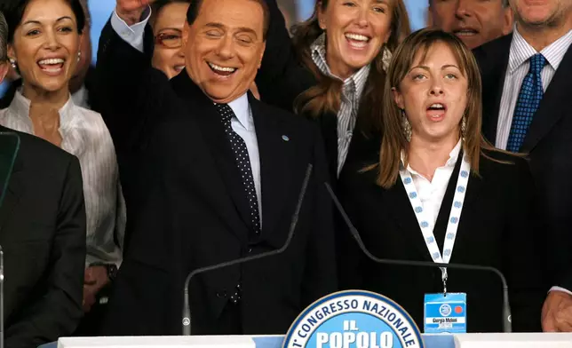 FILE - Italian premier Silvio Berlusconi is flanked by Minister of Equal Opportunities Mara Carfagna, left, Youth Policies Minister Giorgia Meloni, right, and Environment Minister Stefania Prestigiacomo, second from right, during a congress in Rome, March 29, 2009. (AP Photo/Alessandra Tarantino, File)