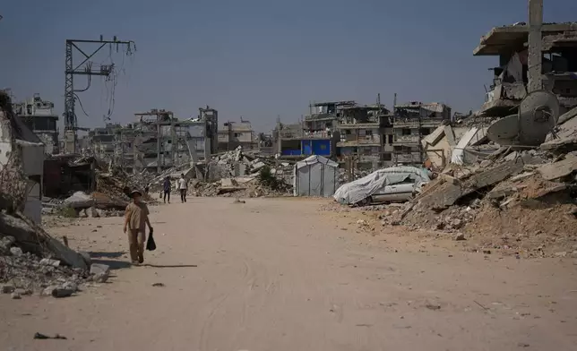 Palestinian walk by the rubble of buildings that were destroyed during the Israel Hamas war, in Khan Younis, southern Gaza Strip, Friday, July 31, 2026. (AP Photo/Abdel Kareem Hana)