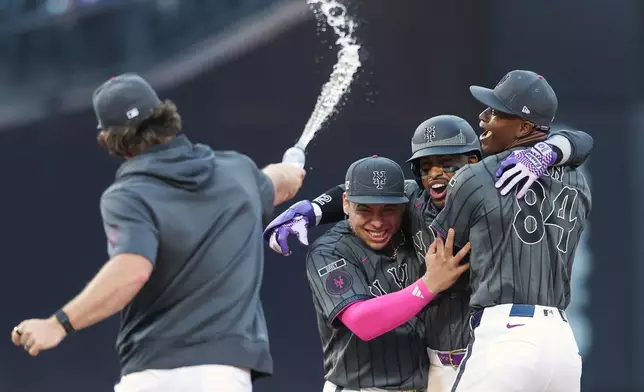 New York Mets' Francisco Lindor, center, celebrates his game winning base hit with pitcher Jefry Yan (84) and Francisco Alvarez, left, during the ninth inning of a baseball game against the Washington Nationals, Saturday, Aug. 15, 2026, in New York. (AP Photo/Heather Khalifa)