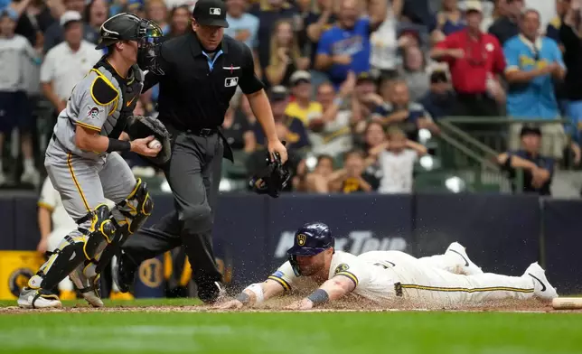 Milwaukee Brewers' Jake Bauers, right, slides into home plate to score a run past Pittsburgh Pirates' Henry Davis during the sixth inning of a baseball game Monday, Aug. 3, 2026, in Milwaukee. (AP Photo/Aaron Gash)