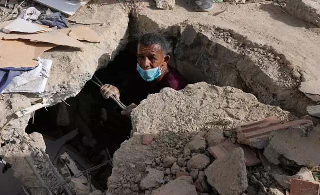 FILE - Franklin Fuentes searches for missing relatives in the collapsed building where they lived two days after earthquakes struck La Guaira, Venezuela, June 26, 2026. (AP Photo/Ariana Cubillos, File)