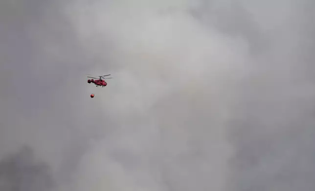 A firefighter's helicopter battles a forest fire in Deliblatska Pescara (Deliblato Sands), near the village of Sumarak, 70 kilometers north-west of Belgrade, Serbia, Thursday, Aug. 20, 2026. (AP Photo/Darko Vojinovic)