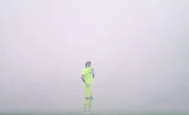 SV Waldhof Mannheim goalkeeper Thijmen Nijhuis covers his face as smoke caused by pyrotechnics lit by fans blankets the stadium during the Germany Cup soccer match between SV Waldhof Mannheim and 1. FC Kaiserslautern, Friday, Aug. 21, 2026, in Mannheim, Germany. (Uwe Anspach/dpa via AP)