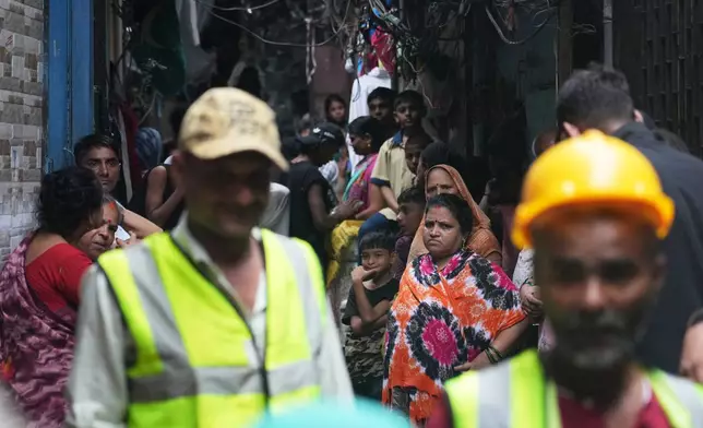 Residents of a slum affected by a landslide gather behind rescue workers in Mumbai, India, Wednesday, Aug. 12, 2026. (AP Photo/Rafiq Maqbool)