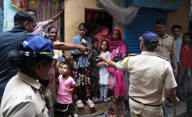 Policemen talk to the residents of a slum affected by a landslide in Mumbai, India, Wednesday, Aug. 12, 2026. (AP Photo/Rafiq Maqbool)