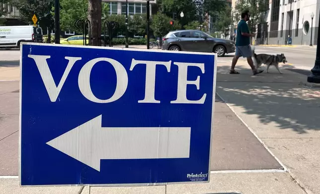 A person walks past a sign for a polling place on the first day of in-person absentee voting for Wisconsin's chaotic Democratic primary for governor Tuesday, July 28, 2026, in Madison, Wis. (AP Photo/Scott Bauer)