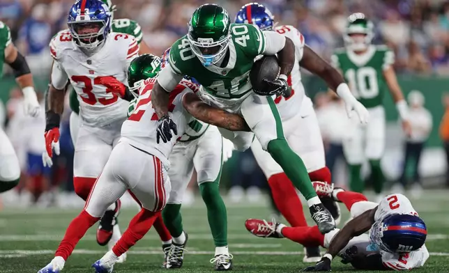 New York Jets running back Chip Trayanum (40) is tackled by New York Giants defensive back Ar'Darius Washington (24) during the first half of a preseason NFL football game, Friday, Aug. 28, 2026, in East Rutherford, N.J. (AP Photo/Adam Hunger)