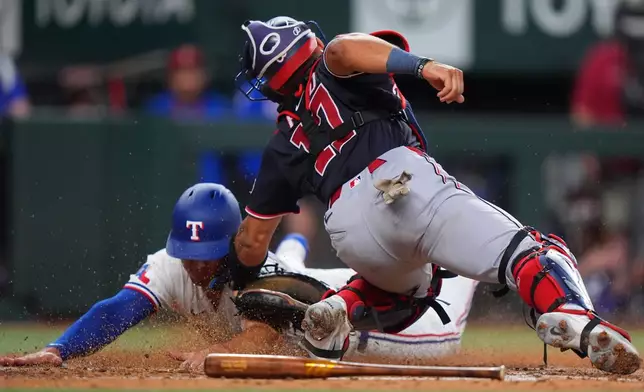 Texas Rangers' Wyatt Langford, left, scores on a fielders choice against Washington Nationals catcher Harry Ford during the third inning of a baseball game, Tuesday, Aug. 18, 2026, in Arlington, Texas. (AP Photo/LM Otero)