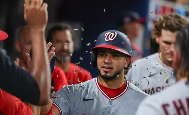 Washington Nationals teammates congratulate Keibert Ruiz, center, after Ruiz hit a solo home run during the sixth inning of a baseball game against the Miami Marlins, Friday, Aug. 21, 2026, in Miami. (AP Photo/David Santiago)