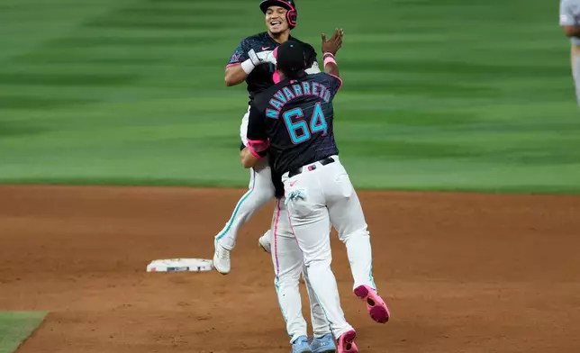 Miami Marlins' Javier Sanoja, top, celebrates with teammates Brian Navarreto (64) and Jakob Marsee, center, after hitting the winning RBI single during the ninth inning of a baseball game against the Washington Nationals, Friday, Aug. 21, 2026, in Miami. (AP Photo/David Santiago)