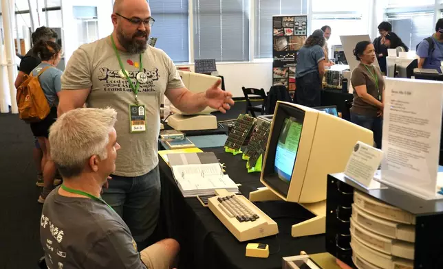 Software engineer Josh Dersch, standing, shows a 1970s Xerox Alto computer he restored at the Vintage Computer Festival in Mountain View, Calif., Sunday, Aug. 2, 2026. (AP Photo/Terry Chea)
