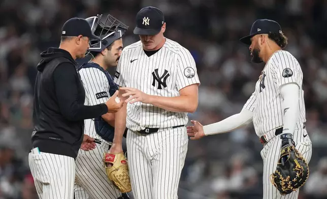 New York Yankees pitcher Brent Headrick, center, hands the ball to manager Aaron Boone, left, as he leaves during the eighth inning of a baseball game against the Houston Astros Tuesday, Aug. 25, 2026, in New York. (AP Photo/Frank Franklin II)