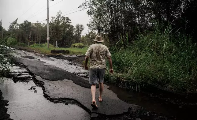 Eric Hubner walks along a washed-out road near his home in Mountain View, Hawaii, Sunday, Aug. 16, 2026, after a severe weather system went through the area. (Stephen Lam/San Francisco Chronicle via AP)