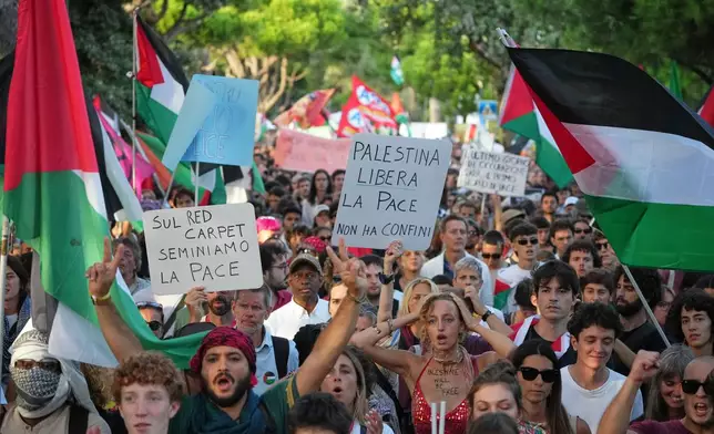FILE - Demonstrators hold placards that read 'On the red carpet lets sow peace' and 'Free Palestine, peace has no borders' during a march in support of the Palestinian people in Gaza, during the Film Festival in Venice, Italy, Saturday, Aug. 30, 2025. (Photo by Alessandra Tarantino/Invision/AP, File)