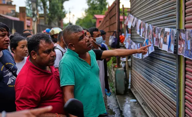 People look at photographs of people killed in flash floods displayed outside a government hospital to help relatives identify the victims in Kathmandu, Nepal, Friday, Aug. 28, 2026. (AP Photo/Dar Yasin)