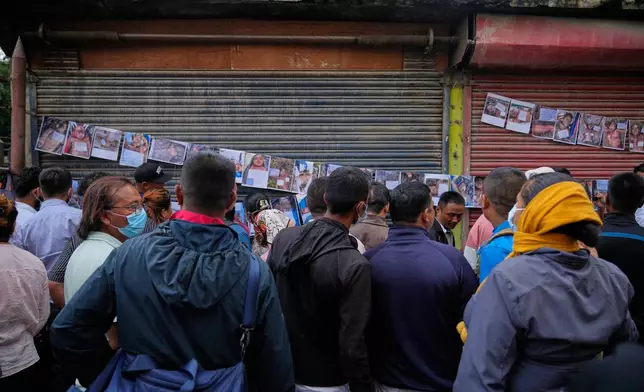 EDS NOTE: GRAPHIC CONTENT - People look at photographs of people killed in flash floods displayed outside a government hospital to help relatives identify the victims in Kathmandu, Nepal, Friday, Aug. 28, 2026