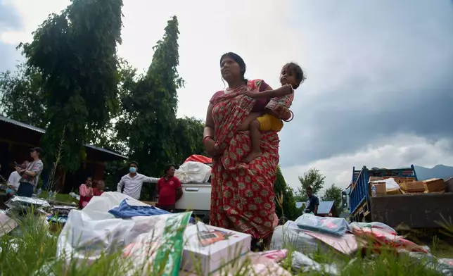 A flash flood survivor arrives to receive relief supplies in the Devighat area of Nuwakot district in Nepal, Friday, Aug. 28, 2026. (AP Photo/Niranjan Shrestha)