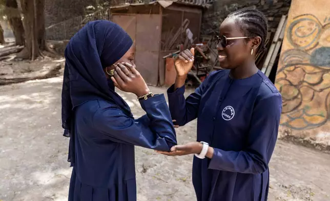 Ndeye Awa Diop, Left, Karine Marteau Kantoussan, Right, play a game at the Mariama Ba School playground in Goree Island, Senegal, Thursday, March 12, 2026. (AP Photo/Caitlin Kelly)