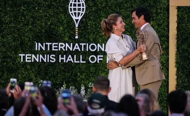 Roger Federer is embraced by his wife Mirka during his induction ceremony at the International Tennis Hall of Fame, Saturday, Aug. 29, 2026, in Newport, R.I. (AP Photo/Charles Krupa)
