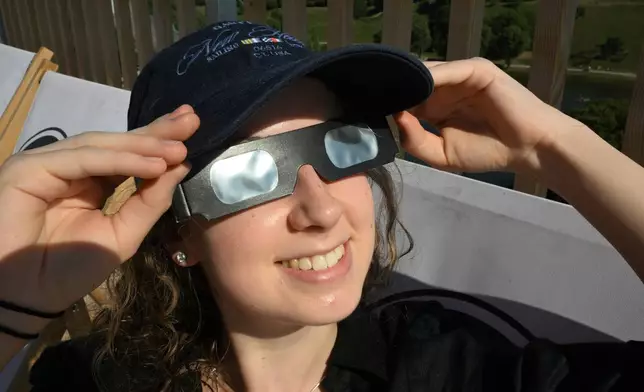 A woman wears safety goggles, as she prepares to watch the partial solar eclipse on the SAYAQ Adventure Tower in Munich's Olympic Park, on Wednesday, Aug. 12, 2026 in Munich, Germany. (Felix Hörhager/dpa via AP)