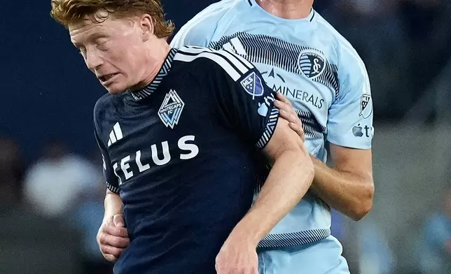 Vancouver Whitecaps' Oliver Larraz (8) gets past Sporting Kansas City's Jacob Bartlett to head the ball during the first half of an MLS soccer match Saturday, Aug. 29, 2026, in Kansas City, Kan. (AP Photo/Charlie Riedel)