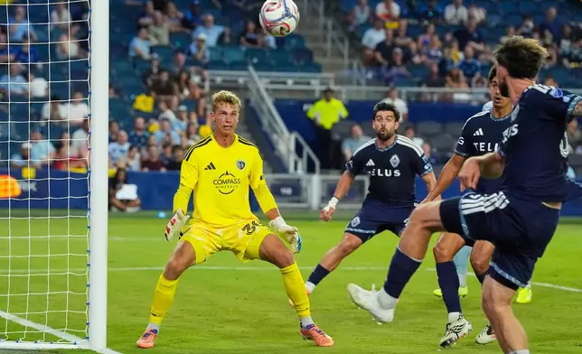 Sporting Kansas City goalkeeper Stefan Cleveland (30) watches a shot by Vancouver Whitecaps' Tristan Blackmon, right, go over the goal during the second half of an MLS soccer match against Sporting Kansas City Saturday, Aug. 29, 2026, in Kansas City, Kan. (AP Photo/Charlie Riedel)