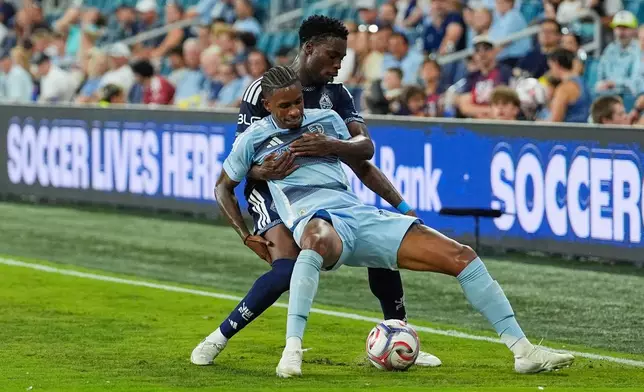 Vancouver Whitecaps' Sam Adekugbe, back, battles for the ball with Sporting Kansas City's Andre Luiz during the second half of an MLS soccer match Saturday, Aug. 29, 2026, in Kansas City, Kan. (AP Photo/Charlie Riedel)