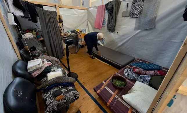 Displaced woman, Fatima Haidar, 51, arranges her makeshift room that set on a basketball court inside a public school turned into a shelter for people whose villages in southern Lebanon were destroyed or occupied by Israeli forces, in Tyre, southern Lebanon, Thursday, Aug. 27, 2026. (AP Photo/Hussein Malla)