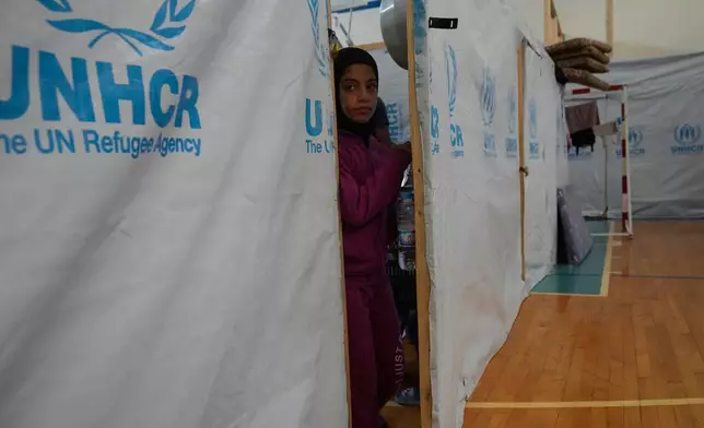 A displaced girl looks trough the door of her makeshift room that set on a basketball court inside a public school turned into a shelter for people whose villages in southern Lebanon were destroyed or occupied by Israeli forces, in Tyre, southern Lebanon, Thursday, Aug. 27, 2026. (AP Photo/Hussein Malla)