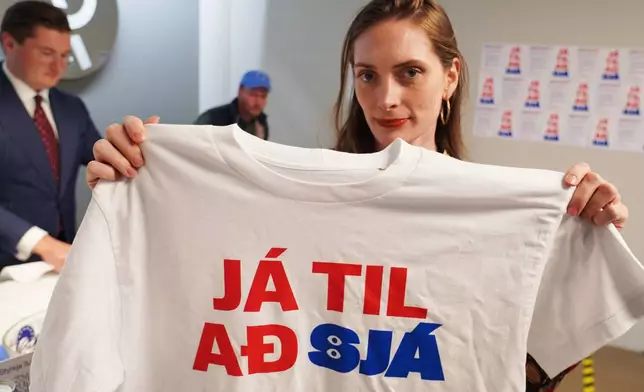 A supporter holds a t-shirt reading, "Yes to see", at the opening of the "Yes" campaign's office in Reykjavik, Iceland, Friday, Aug. 7, 2026. (AP Photo/James Brooks)