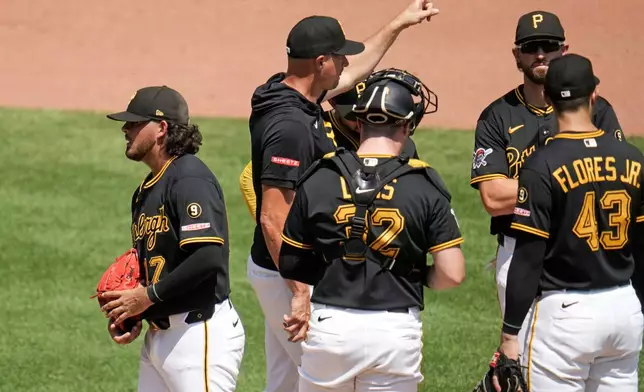 Pittsburgh Pirates pitcher Jared Jones, left, walks off the mound after handing the ball to manager Don Kelly, second from left, during the fourth inning of a baseball game against the New York Mets in Pittsburgh, Sunday, Aug. 9, 2026. (AP Photo/Gene J. Puskar)