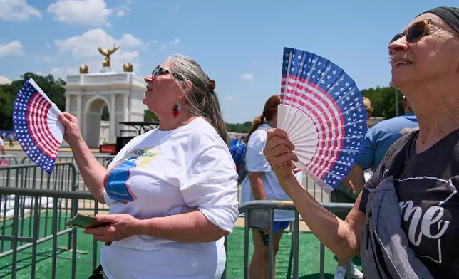 FILE - Mickelina Papotto, of Salem, Ore., left, and Lorie Odegaard, of Gaithersburg, Md., fan themselves while waiting in line for the ferris wheel at the Great American State Fair on the National Mall, July 1, 2026, in Washington. (AP Photo/Jacquelyn Martin, File)