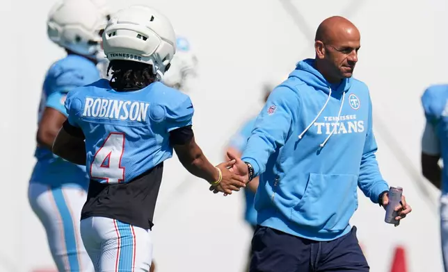 Tennessee Titans head coach Robert Saleh, right, greets wide receiver Wan'dale Robinson (4) during the NFL football team's training camp Tuesday, Aug. 25, 2026, in Nashville, Tenn. (AP Photo/George Walker IV)