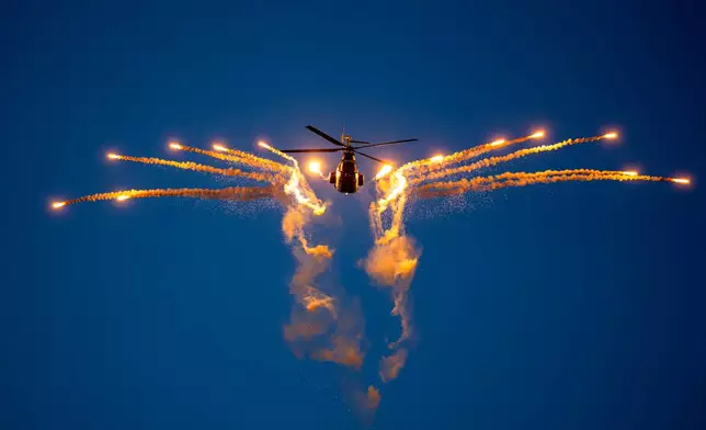 A military helicopter fires flares during the BIAS International Air Show, in Bucharest, Romania, Saturday, Aug. 29, 2026. (AP Photo/Andreea Alexandru)