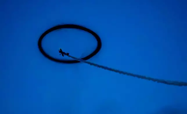 Lithuanian pilot Jurgis Kairys flies through a circle of smoke at the end of the BIAS International Air Show, in Bucharest, Romania, Saturday, Aug. 29, 2026. (AP Photo/Andreea Alexandru)