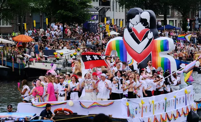People line the Dutch capital's historic canals Saturday, Aug. 1, 2026, to watch the Canal Parade, the most popular event of the Pride Amsterdam festival that attracts tens of thousands of visitors to the city. (AP Photo/Patrick Post)
