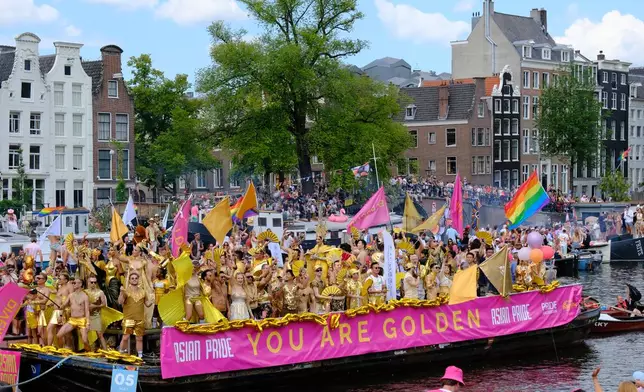 People celebrate atop a boat on one of the Dutch capital's historic canals, Saturday, Aug. 1, 2026, during the Canal Parade, the most popular event of the Pride Amsterdam festival. (AP Photo/Patrick Post)