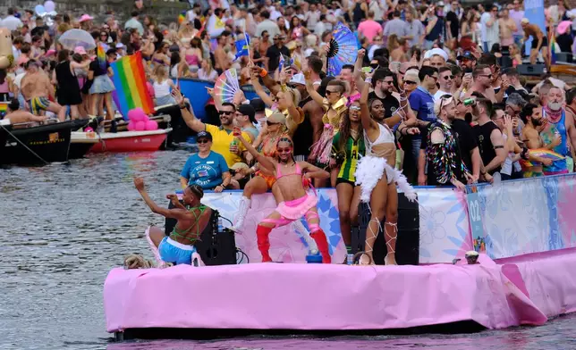 People celebrate atop a boat on one of the Dutch capital's historic canals, Saturday, Aug. 1, 2026, during the Canal Parade, the most popular event of the Pride Amsterdam festival. (AP Photo/Patrick Post)