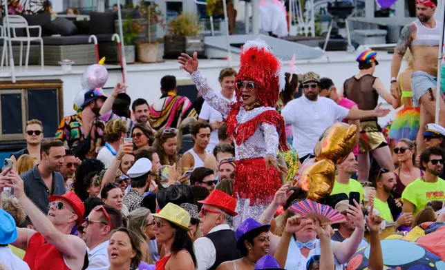 People celebrate atop a boat on one of the Dutch capital's historic canals, Saturday, Aug. 1, 2026, during the Canal Parade, the most popular event of the Pride Amsterdam festival. (AP Photo/Patrick Post)