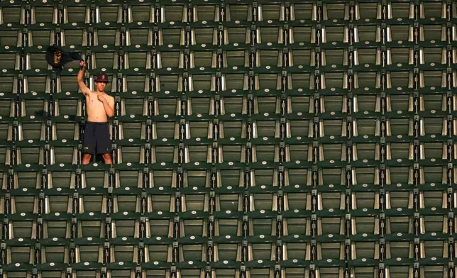 A fan waves their shirt in the nosebleeds during the first inning of a baseball game between the Seattle Mariners and the Philadelphia Phillies, Tuesday, Aug. 25, 2026, in Seattle. (AP Photo/Lindsey Wasson)