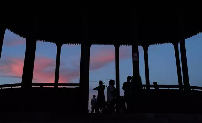 Youngsters play music in a public park as the sun sets in Kyiv, Tuesday, Aug. 25, 2026. (AP Photo/Francisco Seco)