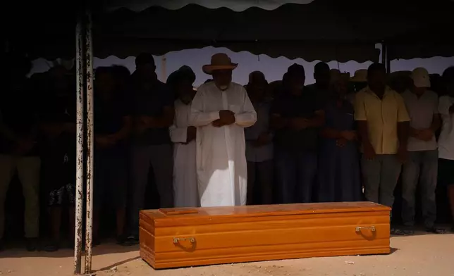 People perform prayers in Ben Guerdane, Tunisia, Wednesday, Aug. 26, 2026, before a burial for migrants who drowned at sea after their boat capsized off the country's southeastern coast. (AP Photo/Bassem Aouini)